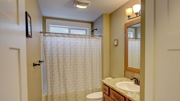 A bathroom with a shower curtain, toilet, sink, and vanity. - A Cozy house in the heart of Gallatin Valley.  (Bozeman)