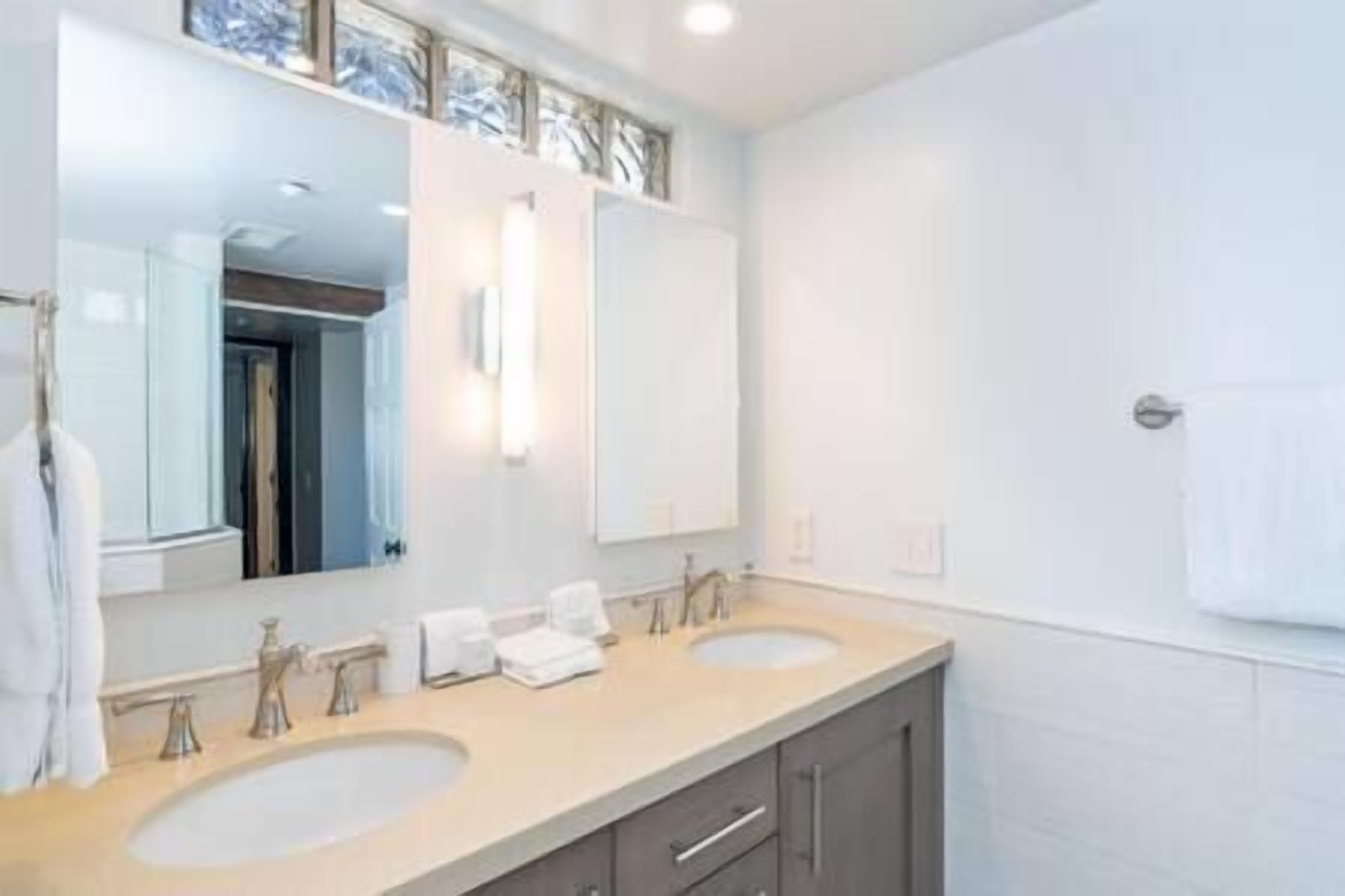 Une salle de bain moderne avec deux lavabos, un grand miroir et un porte-serviettes.