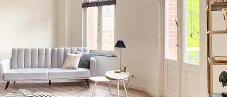 A living room with a grey sofa, a zebra print rug, a small round table, and a floor lamp.