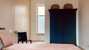 A bedroom with a bed, a chair, a wardrobe, and a window. - Stylish Apartment in Centre of Maastricht (Maastricht)