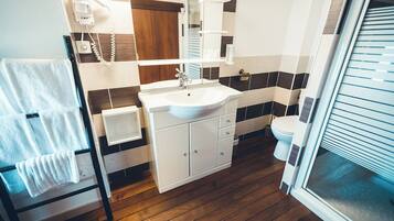 Un baño moderno con suelo de madera, lavabo blanco y un inodoro.