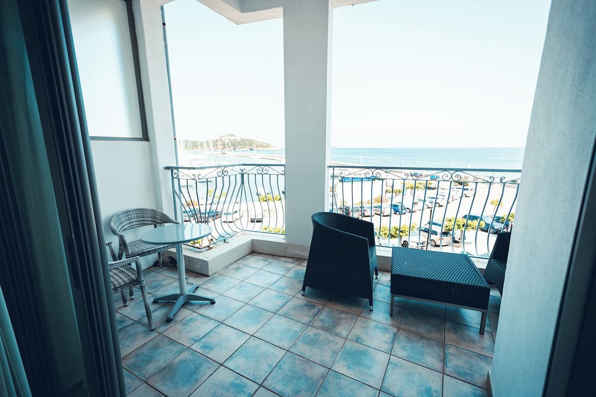 A balcony with a view of the sea, featuring a table and two chairs.