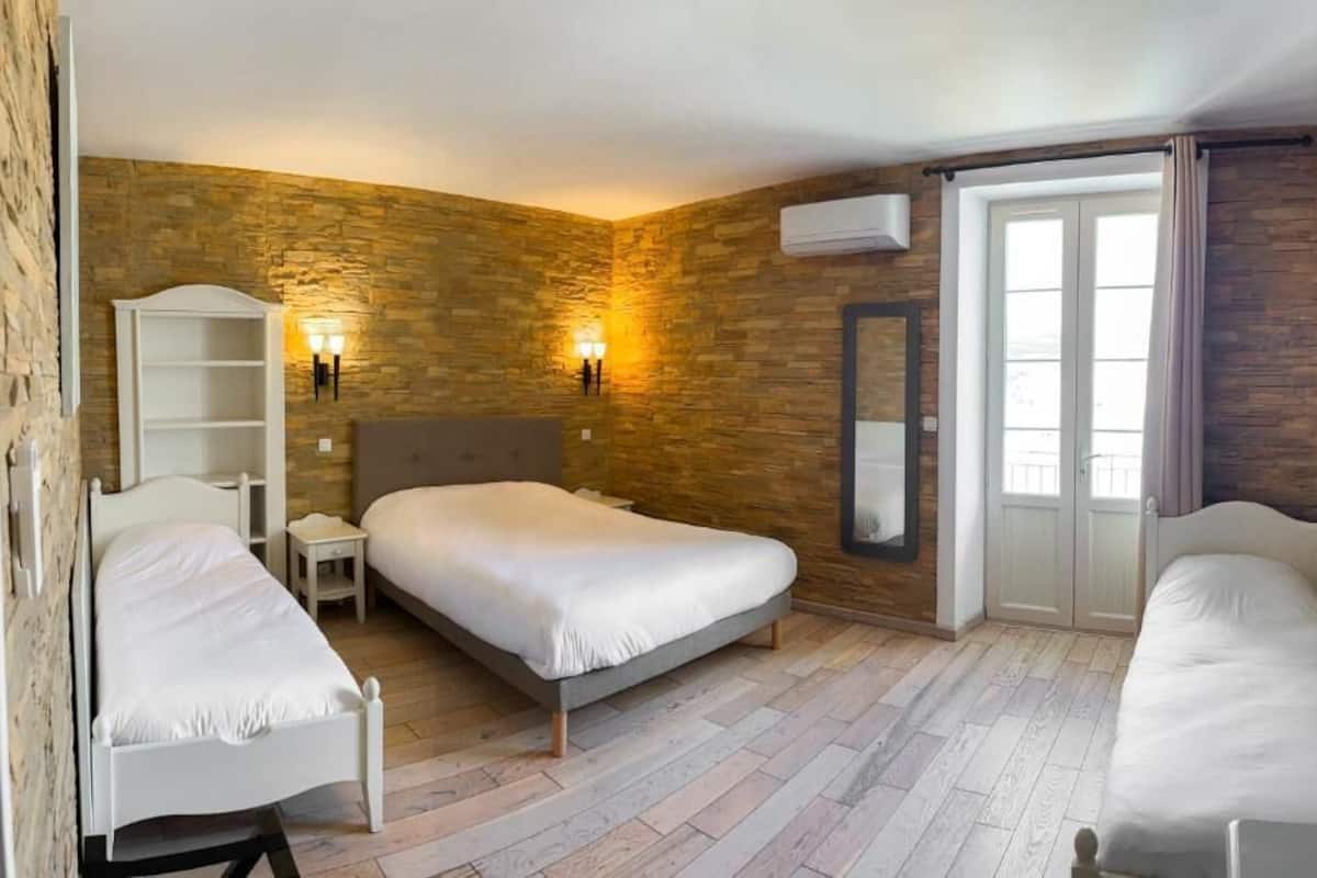 A room with a large bed, two bedside tables, a wardrobe, a mirror, and a window with curtains.