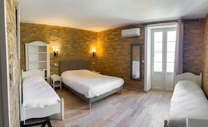 Una habitación con una cama grande, dos mesitas de noche, un armario, un espejo y una ventana con cortinas.