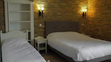 Un dormitorio con dos camas, una mesita de noche, un armario y decoración de pared de piedra.