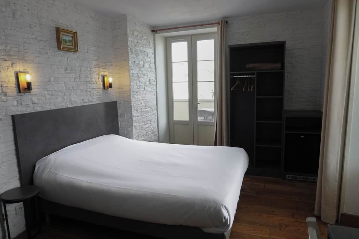 A bedroom with a large bed, a wardrobe, and a window with curtains.