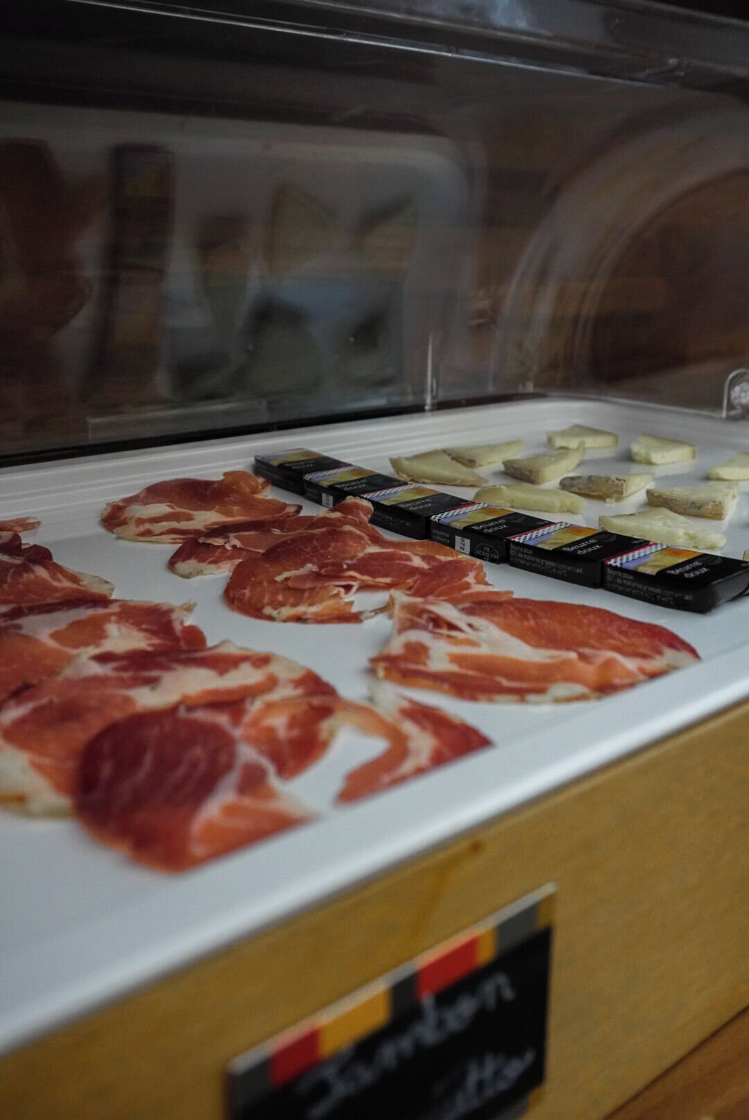 Vitrine com diversos tipos de enchidos e queijos.