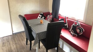 Et hyggeligt spiseområde med et bord og stole, et lille vindue med udsigt, og en vægmonteret aircondition.