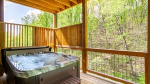 A hot tub on a wooden deck with a view of a forest. - Allure Woods: View, HotTub, Outdoor Dining & Games (Sevierville)