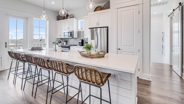 A spacious kitchen with a large island, bar stools, and modern appliances. - Chic, waterfront home with on-site golf, pool, wraparound balcony, grill, & W/D (Port Aransas)