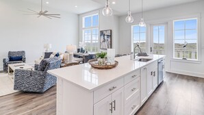 A spacious kitchen with a large island, white cabinetry, and pendant lighting. - Chic, waterfront home with on-site golf, pool, wraparound balcony, grill, & W/D (Port Aransas)
