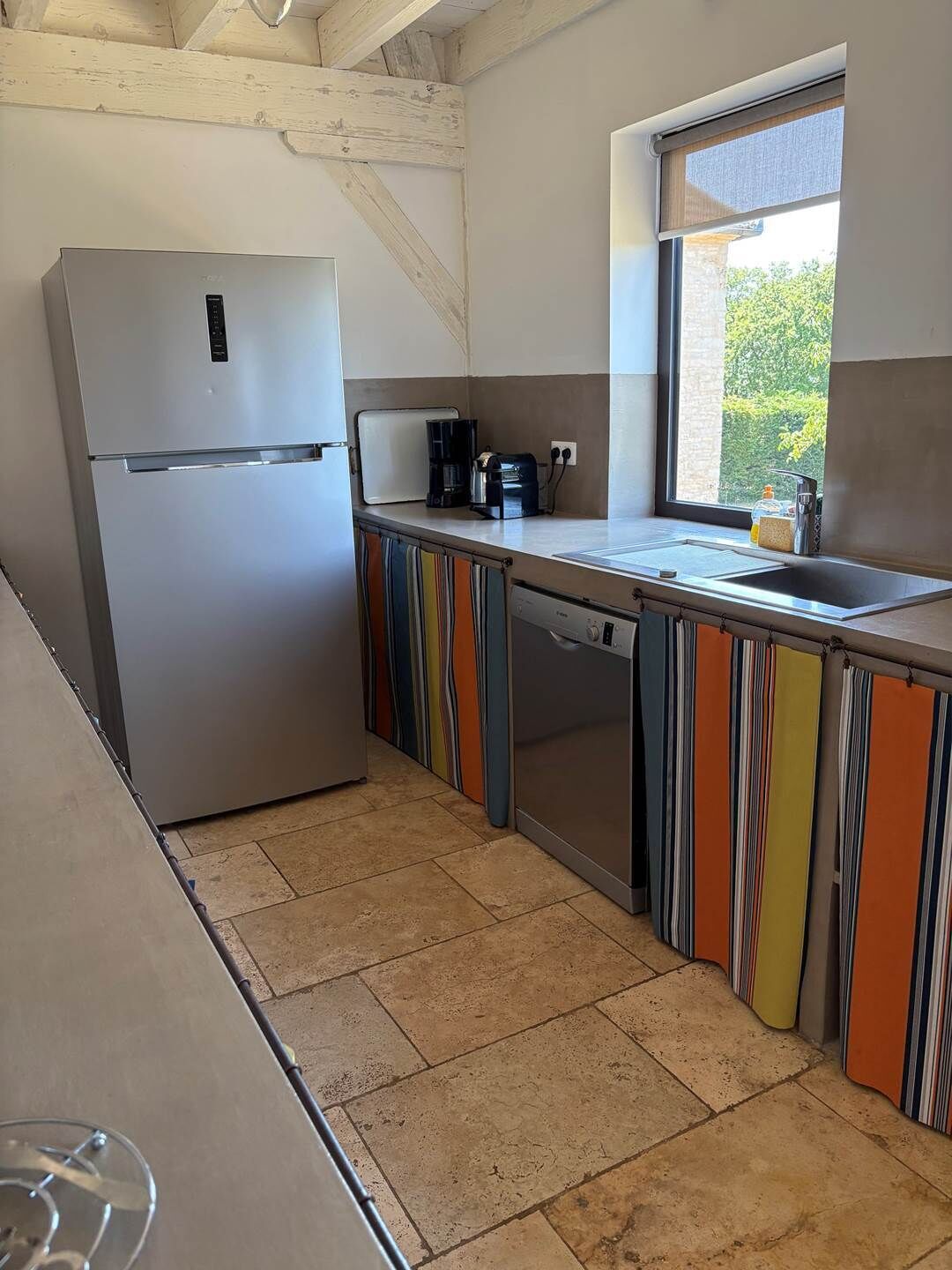 Una cocina compacta con refrigerador, cafetera y ventana con vistas.