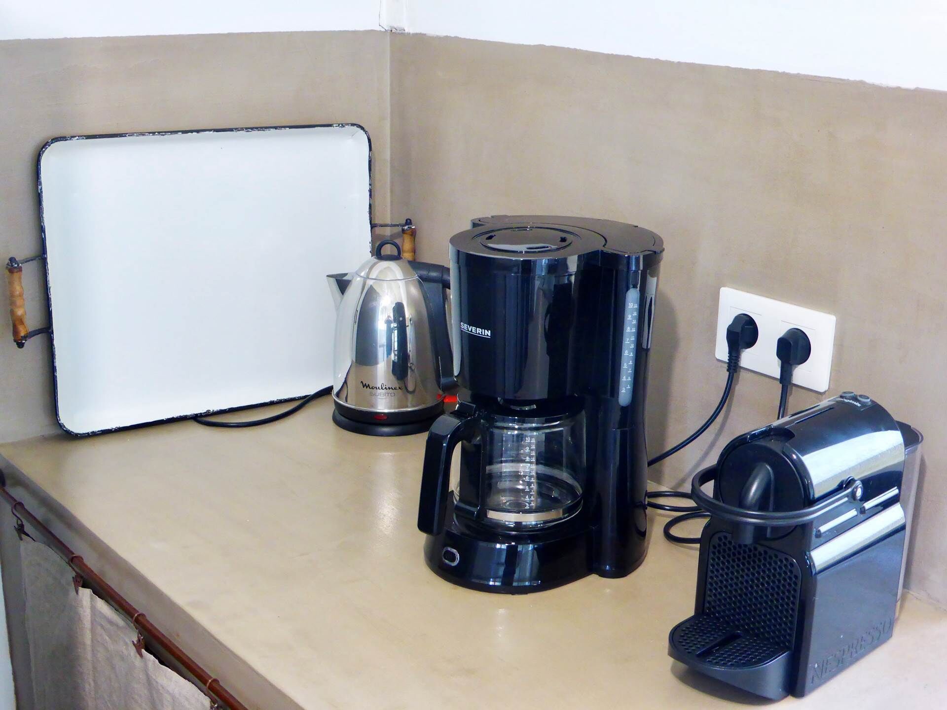 Une petite cuisine équipée d’une machine à café, d’une bouilloire et d’une machine Nespresso.