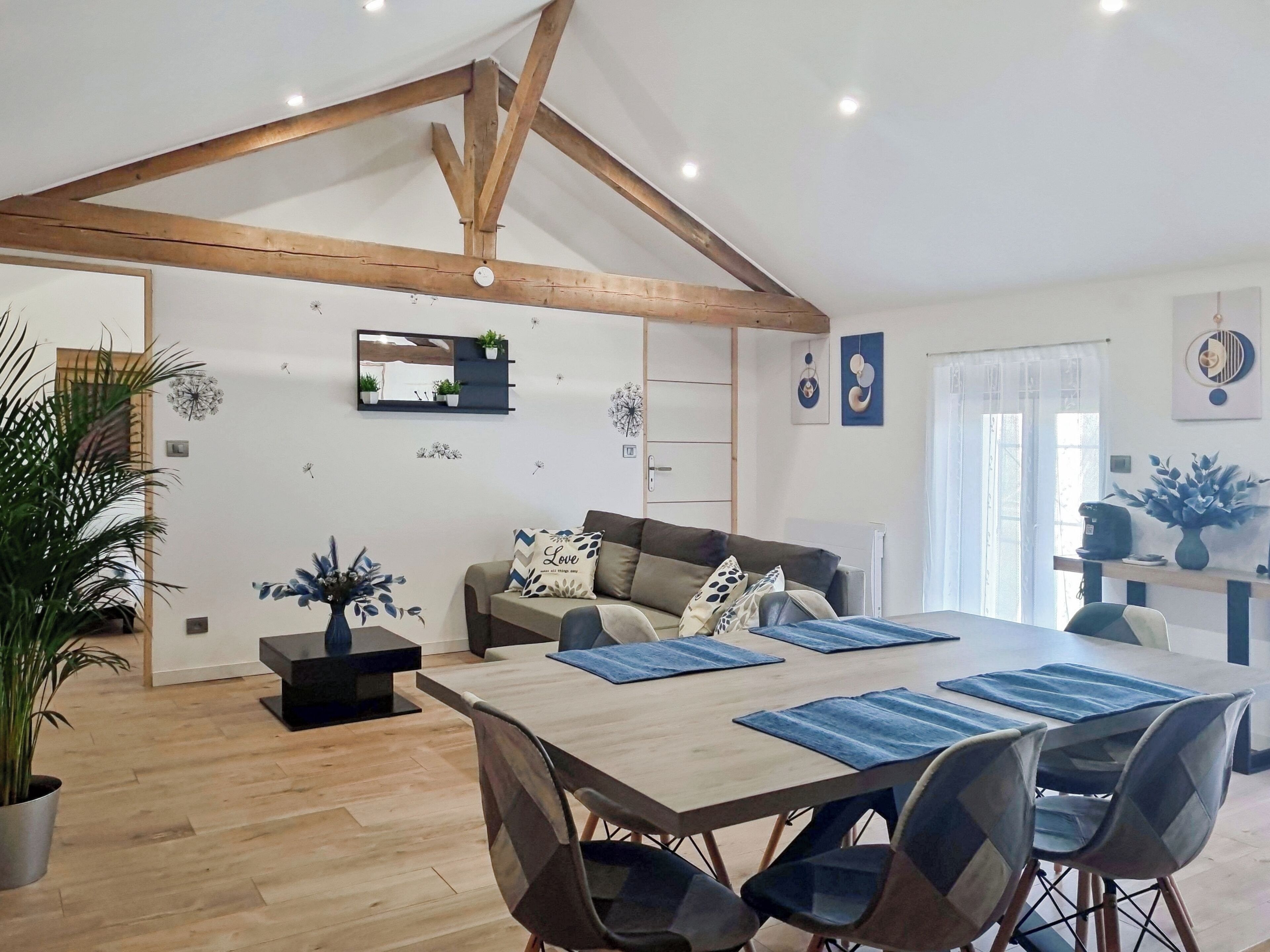 Un salon moderne avec un plafond en bois, un canapé, une table basse et une table à manger avec des chaises.