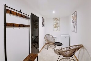 A modern, minimalist room with a wooden bench, two wicker chairs, a small table, and a white radiator.