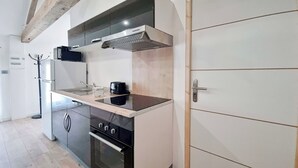 A kitchen with a black stove, a coffee maker, and a wooden beam ceiling.