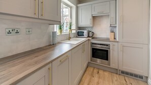 A modern kitchen with light-colored cabinets, stainless steel appliances, and a wooden countertop. - Discover coastal comfort with your perfect retreat in the heart of Beadnell. (Beadnell, near Chathill)