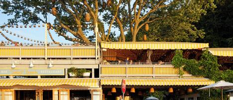 A restaurant with outdoor seating, a stop sign, and a large tree in the background.