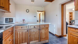 A modern kitchen with wooden cabinets, a white countertop, and a built-in microwave.