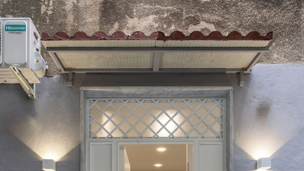 L’entrée d’un hôtel, avec une façade à l’aspect pierre, une grille décorative et deux lampes fixées au mur.