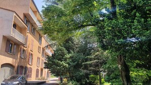 A residential building with multiple balconies, a car parked in front, and a well-maintained garden area. - Charmant Studio vue Montagne Proche Ville et Thermes (Digne-les-Bains)