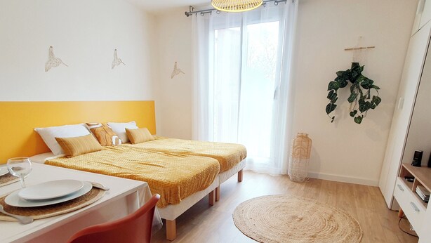 A bedroom with two beds, a dining table, and a chair. - Charmant Studio vue Montagne Proche Ville et Thermes (Digne-les-Bains)