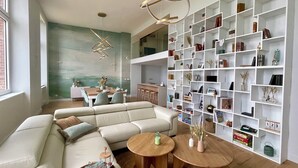 A modern living room with a sectional sofa, a wooden coffee table, and a bookshelf filled with books and decorative items. - Face MER Pieds Dans L'eau Duplex 4 Chambres 150 M2 8-12 Personnes, Parking ,wifi (Berck)