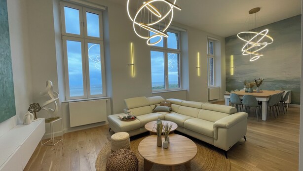 A modern living room with a sectional sofa, a round coffee table, and a dining area with a wooden table and chairs. - Face MER Pieds Dans L'eau Duplex 4 Chambres 150 M2 8-12 Personnes, Parking ,wifi (Berck)