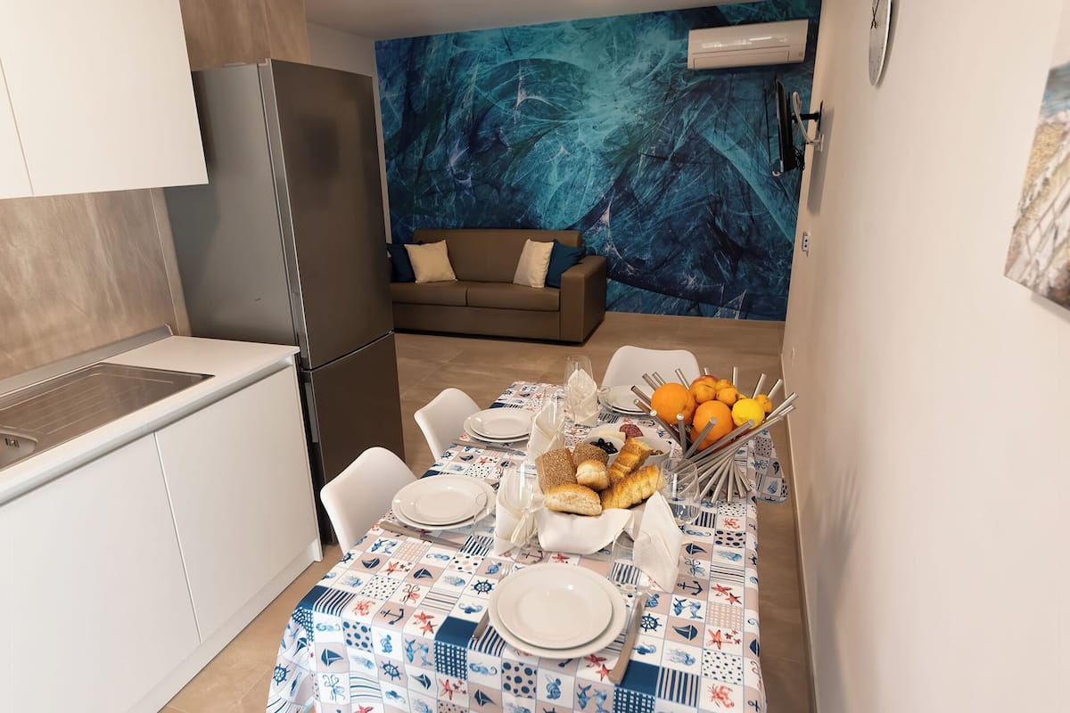 A compact kitchen with a dining area, a sofa, and a decorative wall.