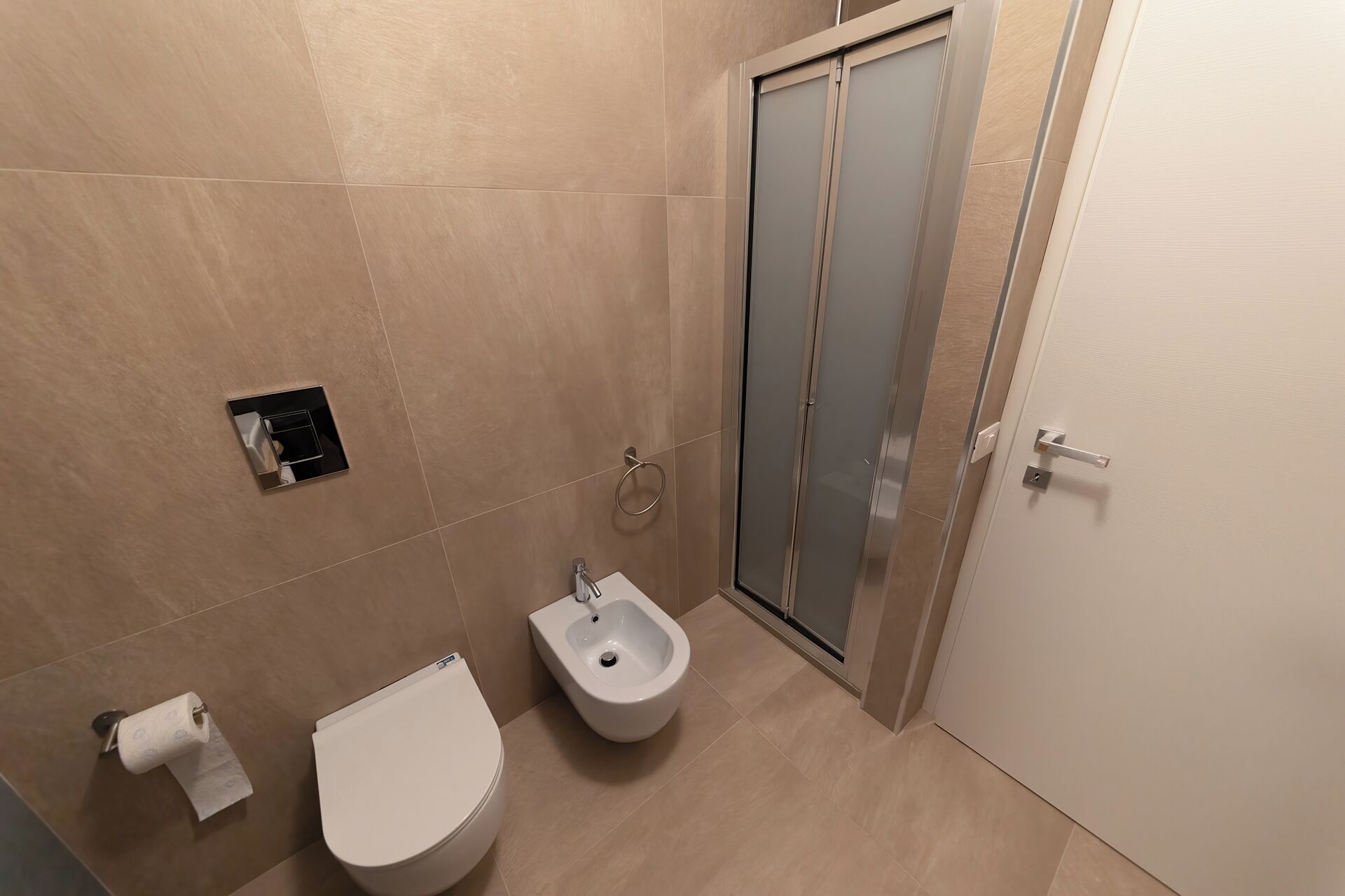 Ein Badezimmer mit Toilette, Bidet und einer Duschkabine aus Glas.