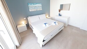 A modern hotel room with a bed, bedside tables, a nightstand, a dresser, and a painting on the wall. - Altamarea Sea Apartments (Balestrate)