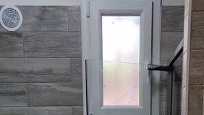 Un bagno con doccia, portasciuga asciugamani, un cesto in vimini e un tappetino blu.