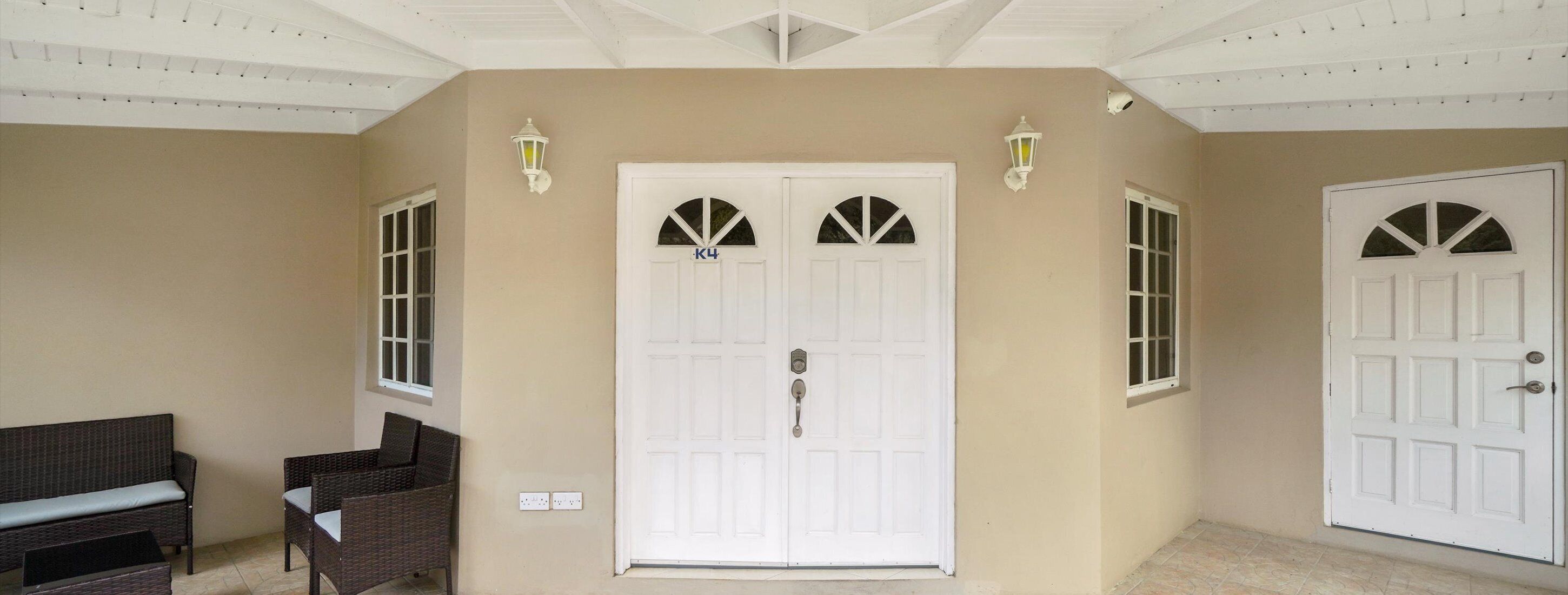 Un pasillo con una puerta doble, dos luces empotradas en la pared y un banco.