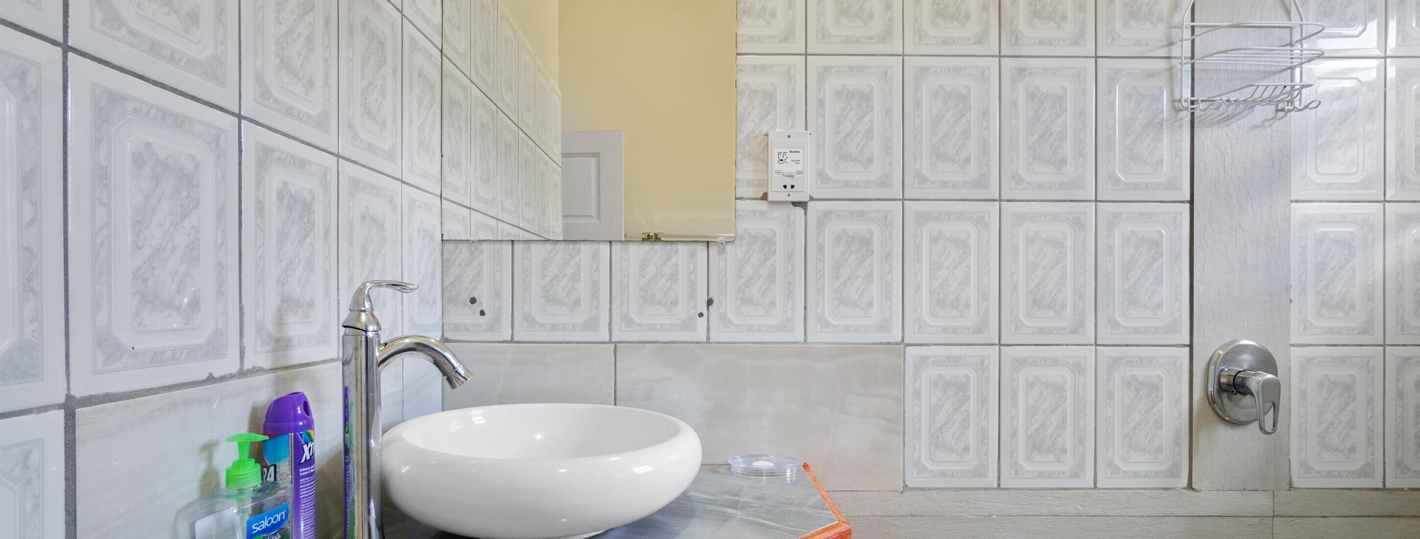 A bathroom with a white sink, a mirror, and a shower area.