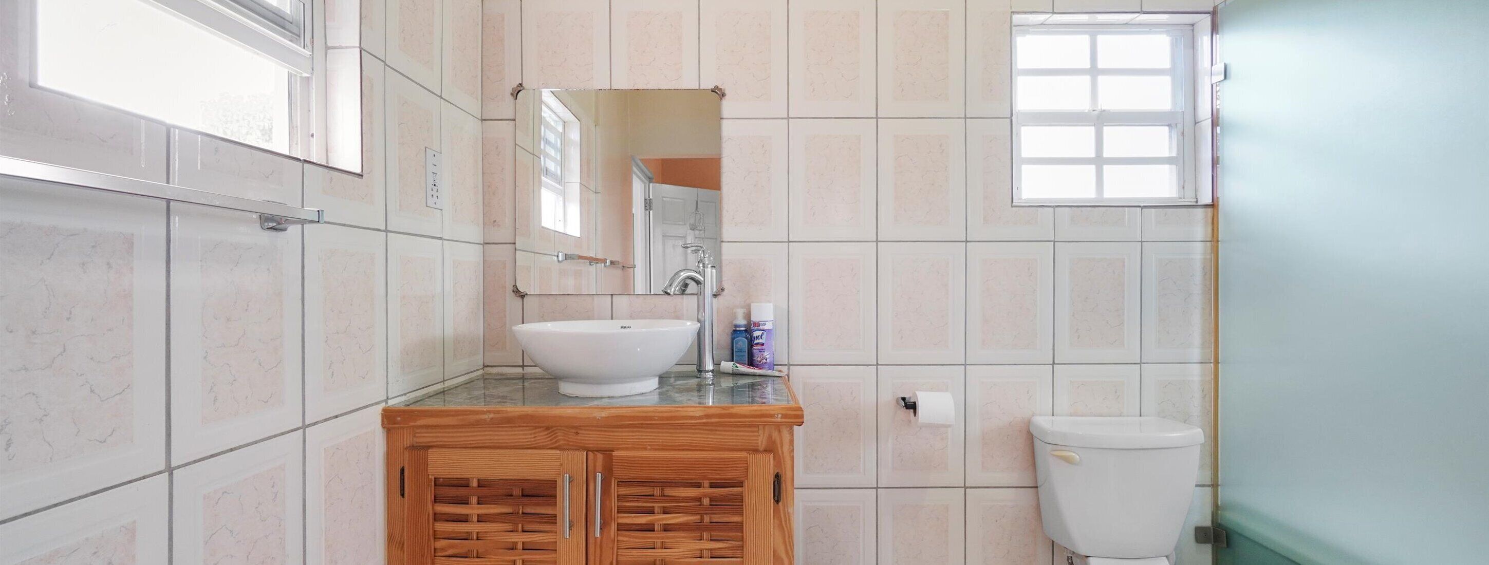 A bathroom with a white sink, wooden vanity, and a toilet.