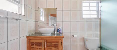 A bathroom with a white sink, wooden vanity, and a toilet.