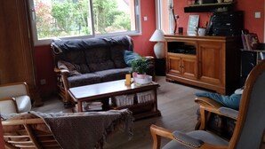Un salon comprenant un canapé, une table basse, un téléviseur et un meuble en bois.