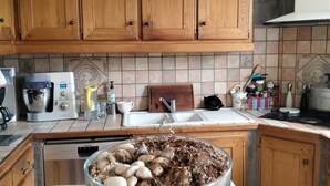 Une cuisine avec des meubles en bois, un lave-vaisselle Siemens, une machine à café et un saladier de champignons.