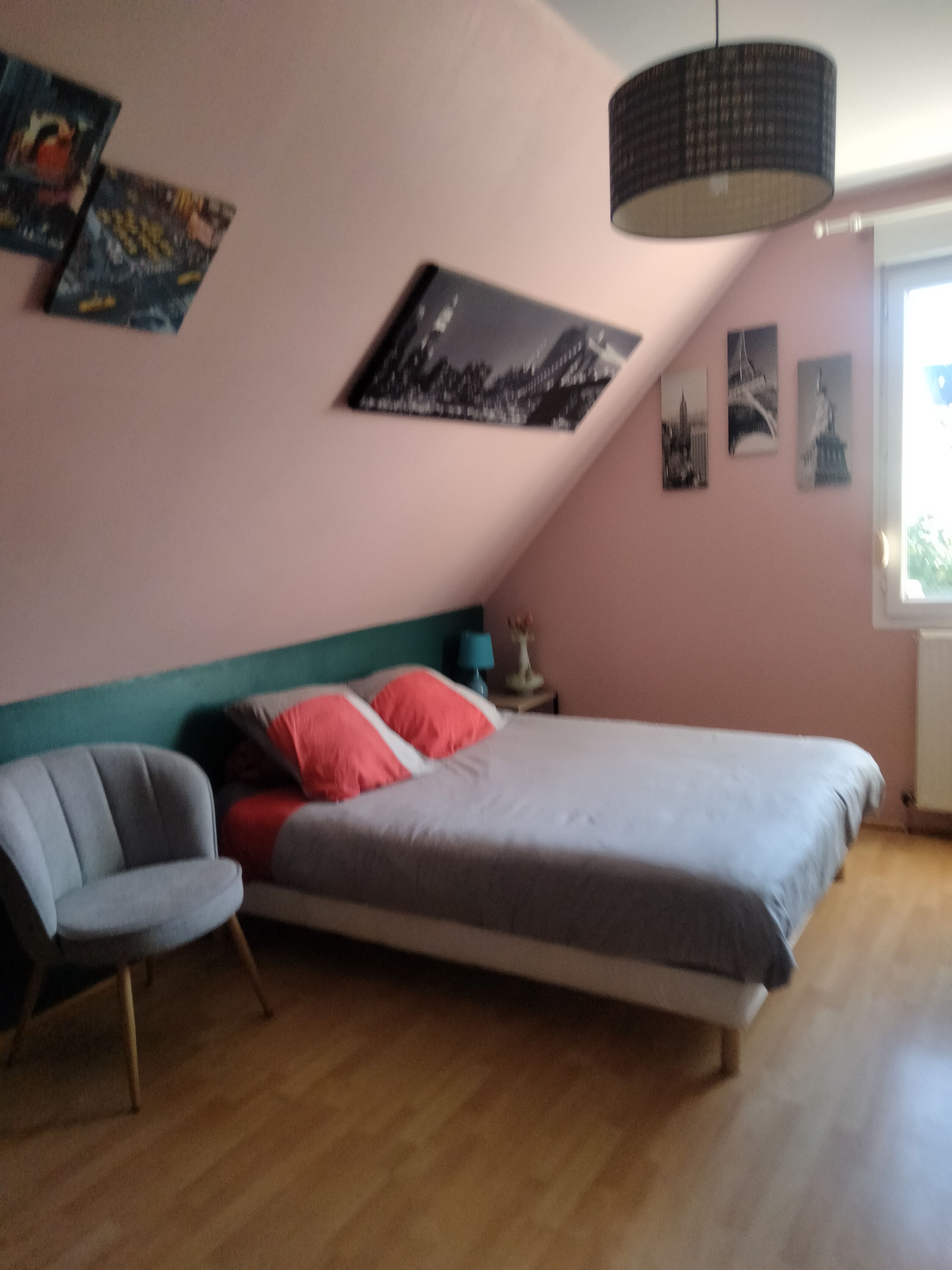 Une chambre à coucher avec un lit, une chaise et un mur décoré de tableaux.