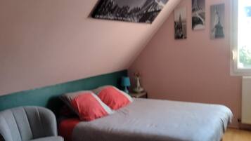 Une chambre à coucher avec un lit, une chaise et un mur décoré de tableaux.