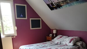 Un dormitorio con una cama, una ventana y un cuadro de un paisaje urbano en la pared.
