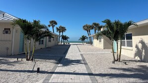 A pathway leading to a beach with palm trees and a building with a number sign. - Bayview Oasis on Casey Key with canal view - short walk to private beach! (Nokomis)