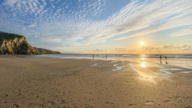 Ein Strand mit Fußabdrücken und einem Sonnenuntergang.