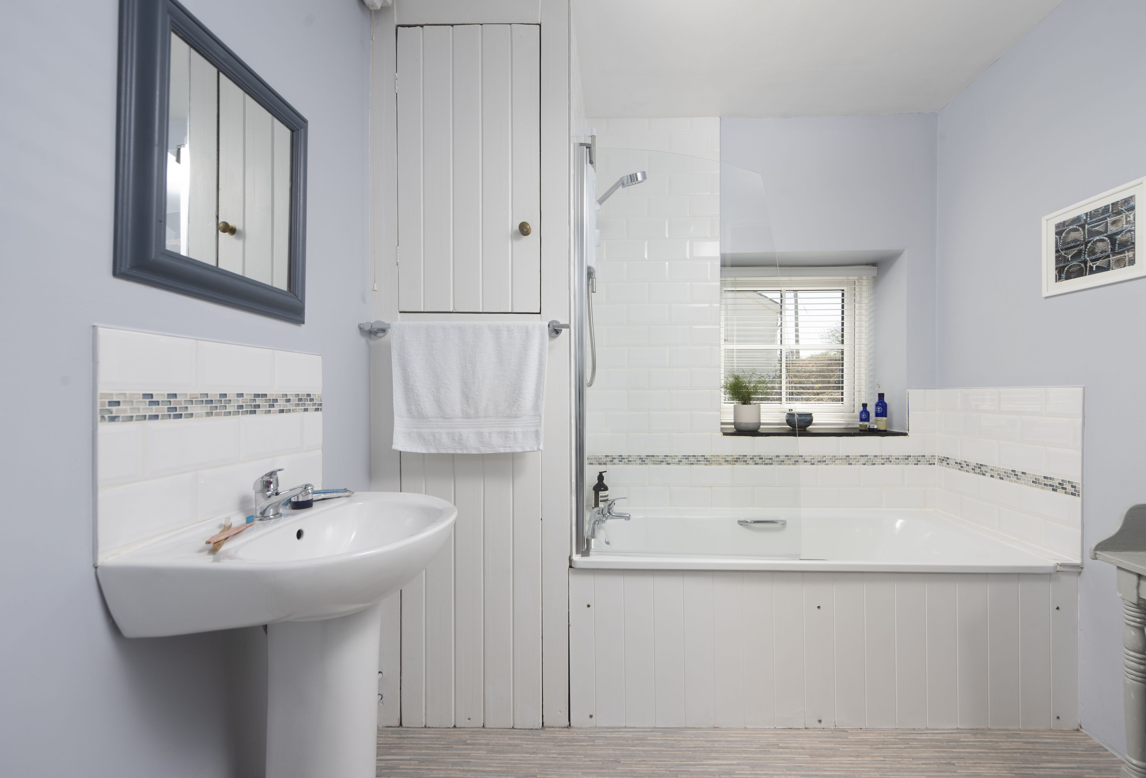 A bathroom with a sink, mirror, towel rack, and a bathtub.