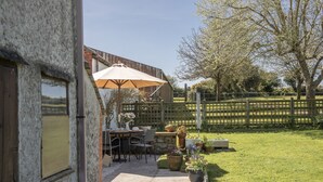 Ein Patio mit Tisch und Stühlen, einem Holzzaun und Blumentöpfen.