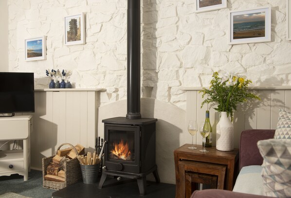 A cozy living room with a stone wall, a fireplace, a TV, and a comfortable seating area.