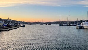 Ein Yachthafen mit vertäuten Booten, eine Uferpromenade und Gebäude im Hintergrund.
