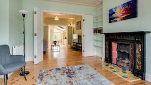 A room with a fireplace, a colorful rug, and a chair. - Summertown 4-BR Family Home - Bright & Spacious (Oxford)