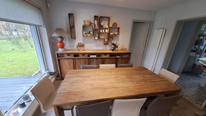 A modern kitchen with a wooden dining table and chairs, built-in shelves, and a view of the outdoors. - Villa touquettoise near the sea (Le Touquet-Paris-Plage)