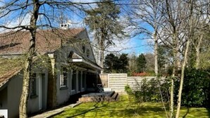 A house with a sloped roof, a front porch, and a well-maintained lawn. - Villa touquettoise near the sea (Le Touquet-Paris-Plage)